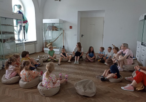 Dzieci siedzą w kole na lekcji w muzeum.