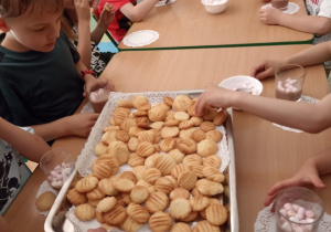 Dzieci w przedszkolu jedzą maślane ciasteczka.
