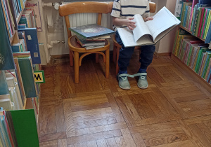 Chłopiec czyta książkę w bibliotece.