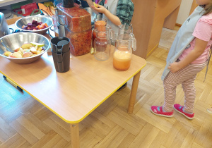Dzieci w sali przedszkolnej robią soki owocowo-warzywne.