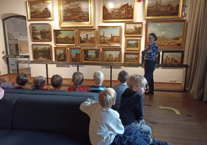 Dzieci podczas wizyty w Muzeum Warszawy oglądają obrazy.