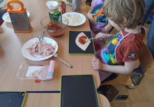 chłopiec smaruje sosem pizzę