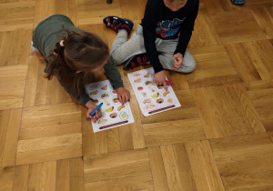 Dzieci wypełniają karty pracy na temat zdrowego żywienia.