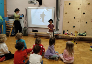 Dzieci na sali gimnastycznej biorą udział w zajęciach na temat kina niemego.