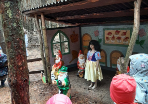 Dzieci słuchają bajki i oglądają figurki w lesie