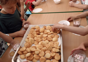 Dzieci w przedszkolu jedzą maślane ciasteczka.