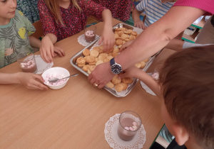 Dzieci w przedszkolu jedzą maślane ciasteczka.