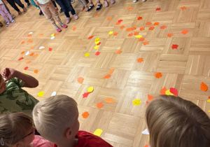 Dzieci w przedszkolu oglądają kolorowe liście z papieru.