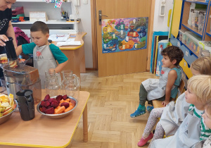 Dzieci w sali przedszkolnej robią soki owocowo-warzywne.