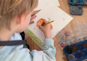 Chłopiec maluje dynię.