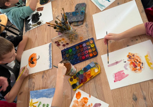 Dzieci wspólnie malują dynie na warsztatach.