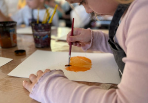 Dziewczynka maluje dynię.