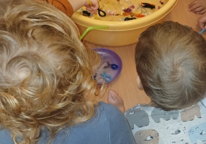 Dzieci za pomocą słomek łowią druciane rybki.