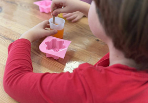 dziewczynka w czerwonej bluzeczce, miesza zabawioną glicerynę