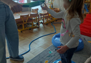 Dziewczynka ćwicząc przypina spinacze na szarfę