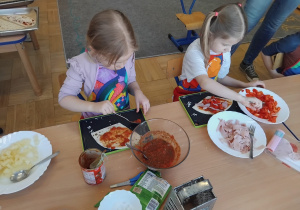 dzieci przygotowuja swoją pizzę